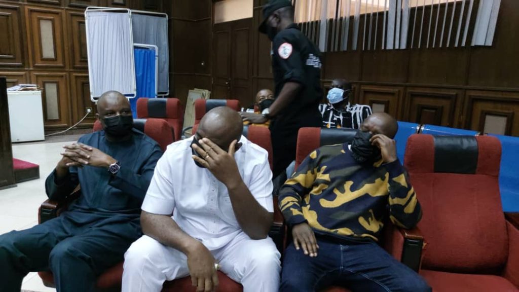 Three men seated in a courtroom.